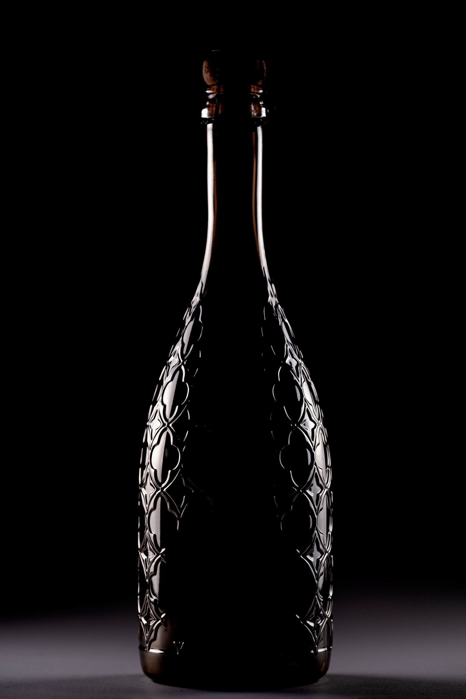 a dark silhouette of a beautiful sparkling wine bottle showing the details of the signature Dogal design. 