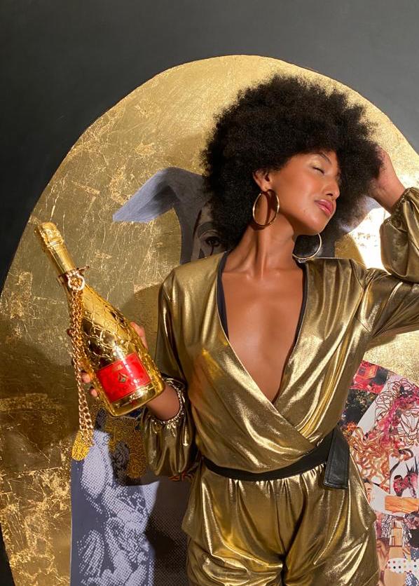 Dark-skinned model dressed in gold robe holding Dogal Sparkling wine Venezia 421 Gold bottle