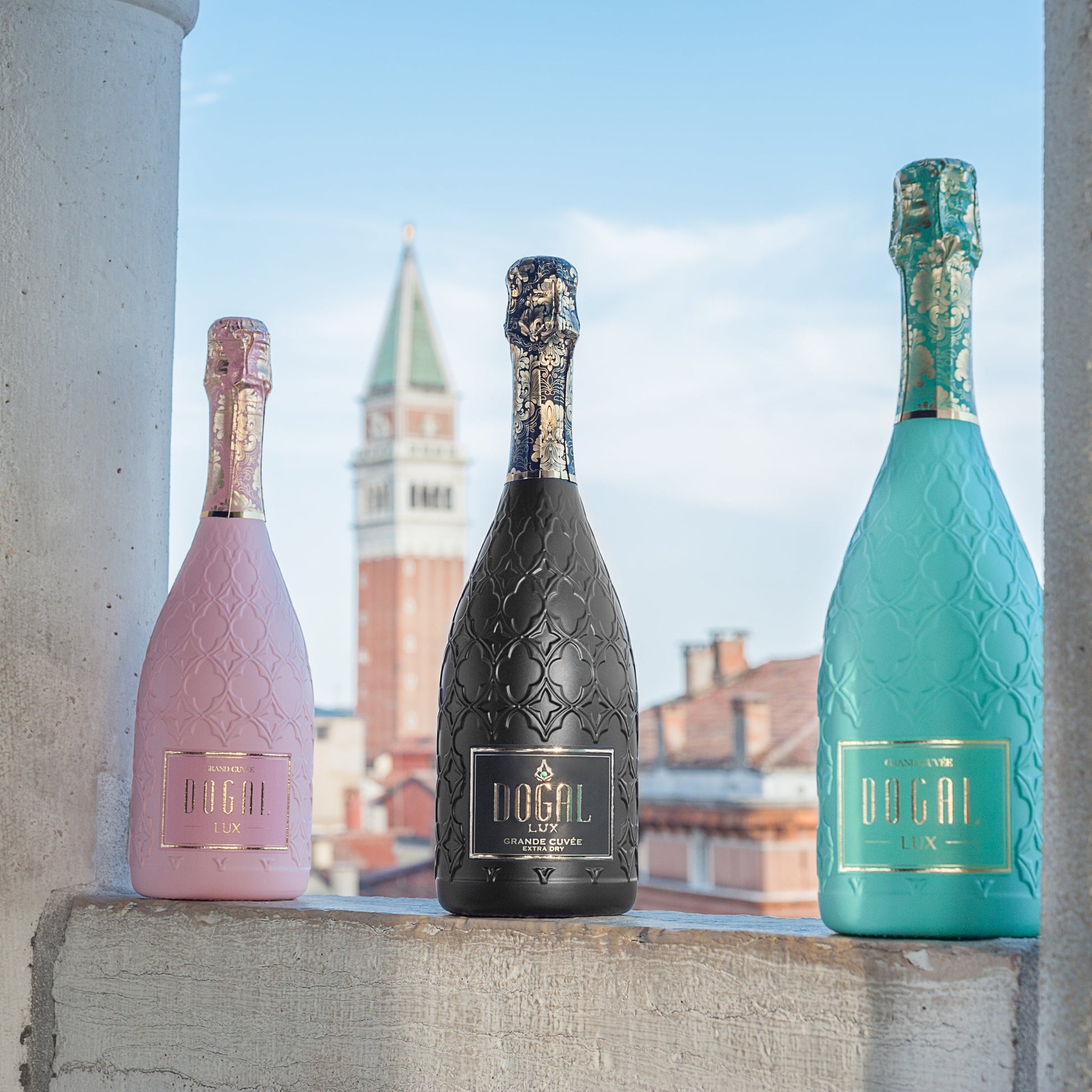 Three bottles from the Dogal Lux Collection, showcasing Pink, Black and Tiffany Blue with the tower of St Mark in the background